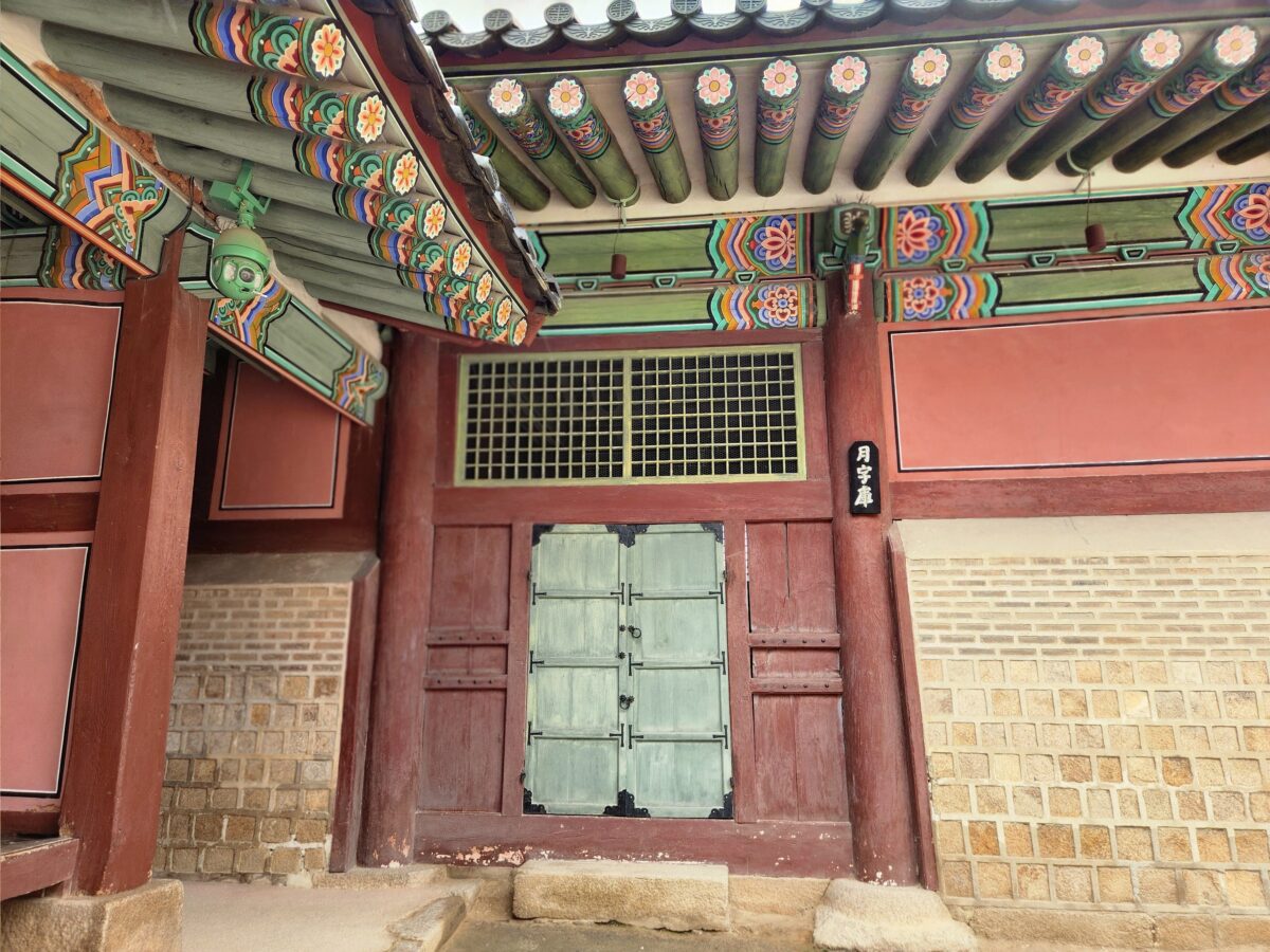A closed gate inside Gyeongbokgung Palace with colorful dancheong patterns on the eaves above