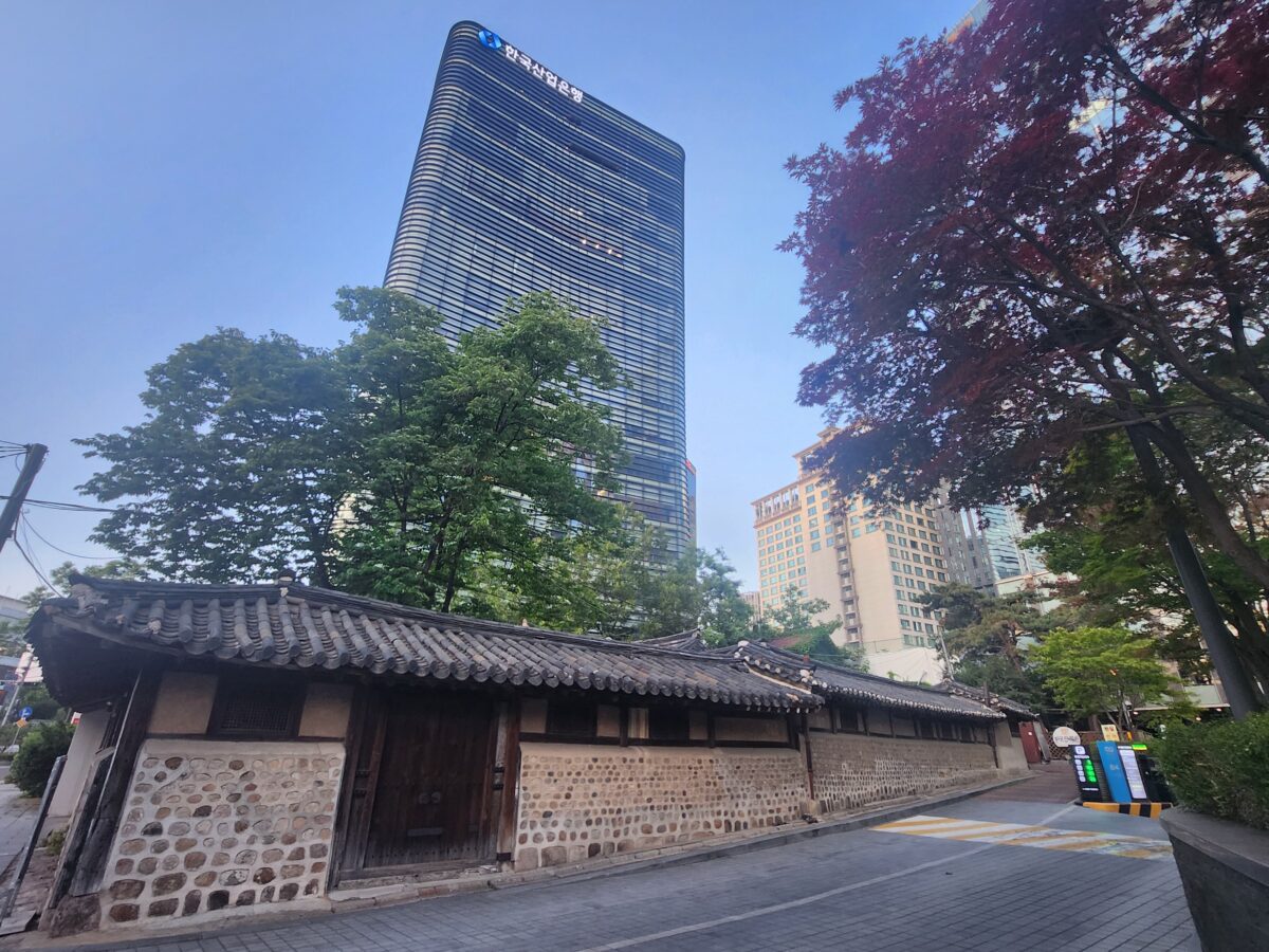 Traditional hanok wall beside modern skyscraper — yin yang korean astrology cycle layers in K-Saju