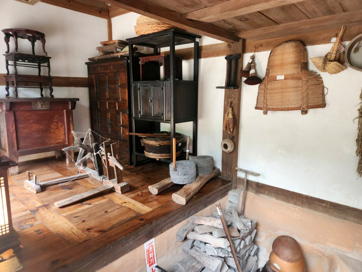 Traditional Korean household tools inside a hanok — millstone, weaving frame, and woven baskets used in daily fermentation and preservation