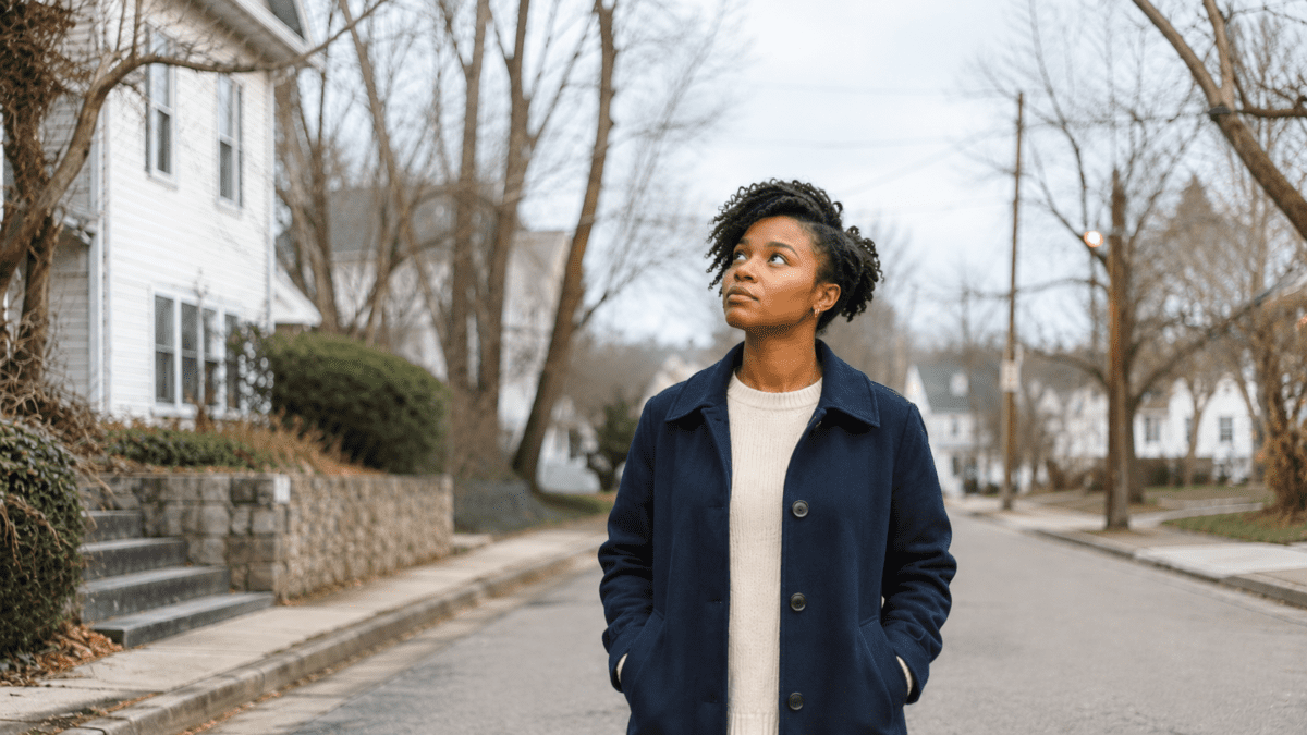 A woman stands alone on a quiet street under an overcast sky, sensing a consolidation phase, a quiet season MBTI and timing read in different ways