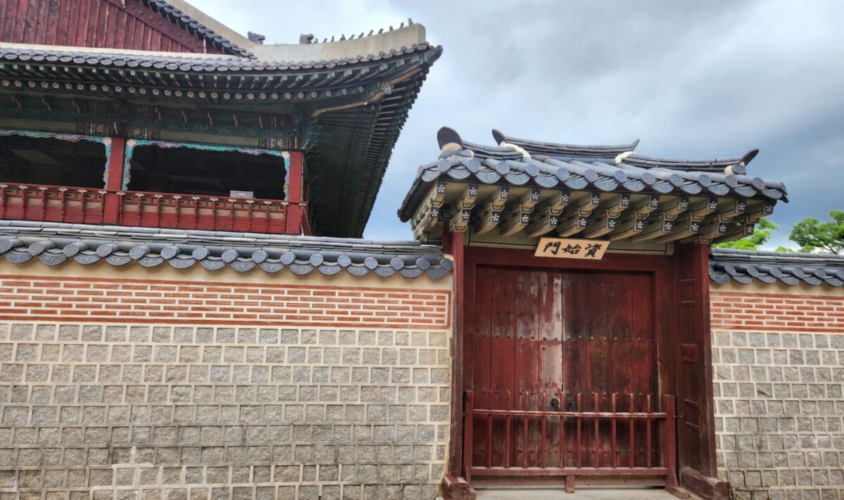 Frozen ground cycle meaning shown through a closed gate at a Korean palace wall under overcast sky