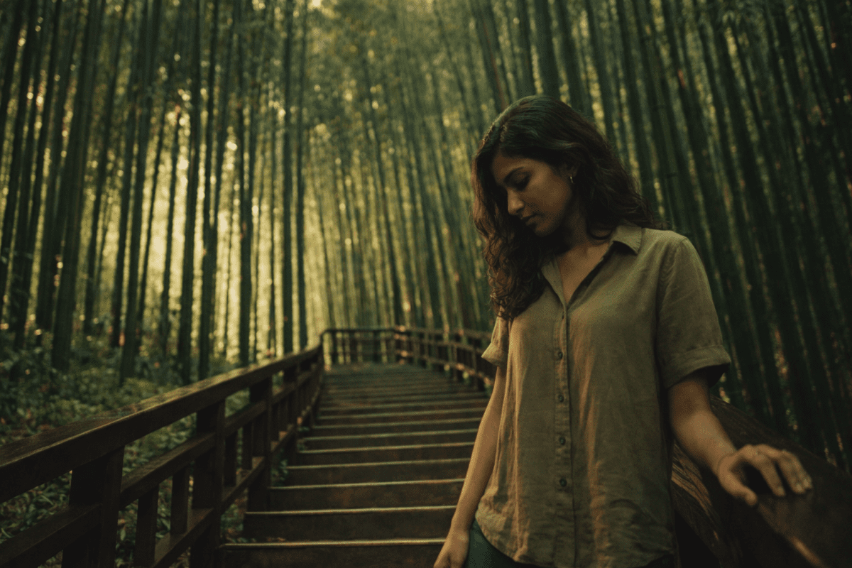 can't stop thinking about work — woman stopped on bamboo forest staircase