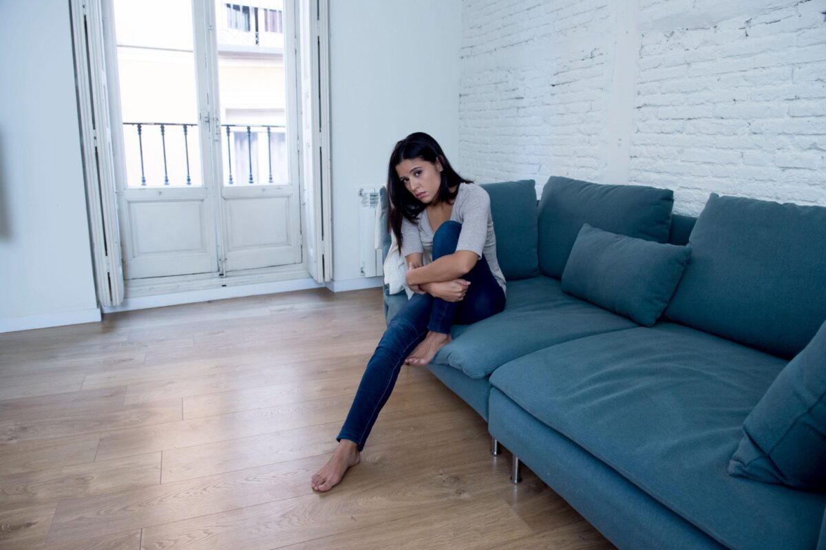Woman stuck in the wrong major, sitting isolated on couch, contemplating her situation