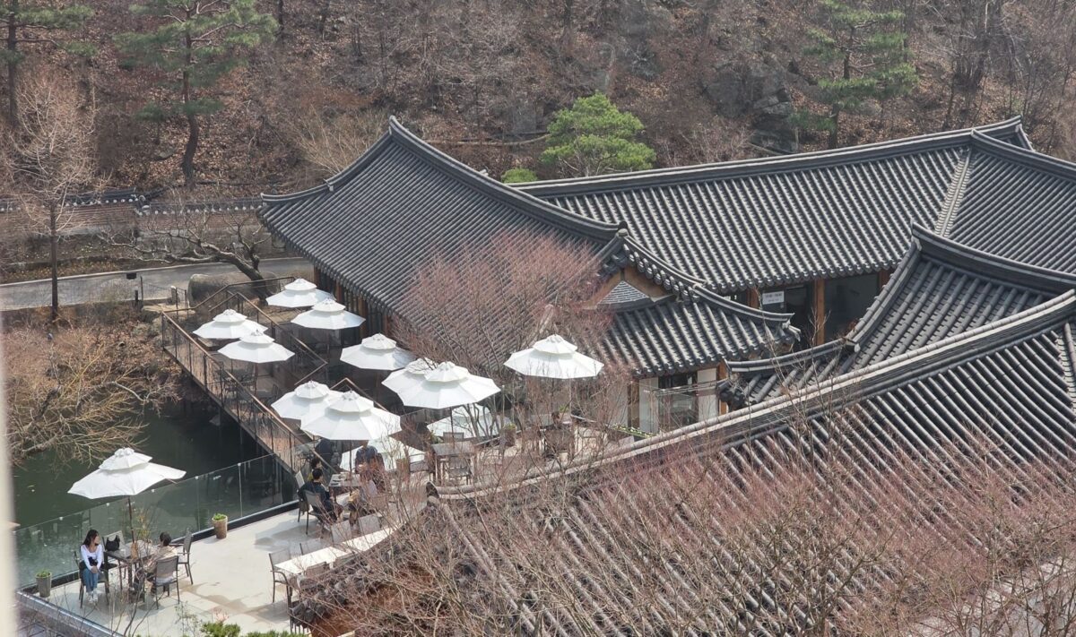 frozen ground cycle meaning — hanok tiled rooftops and a terrace resting beside a quiet pond in late winter