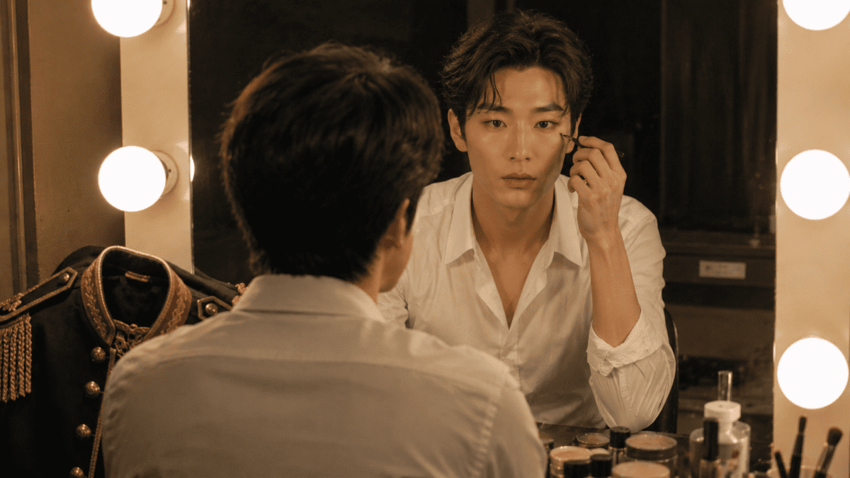 Performer applying eye makeup at a mirror before going on stage, the same ritual of focus before a hard thing.