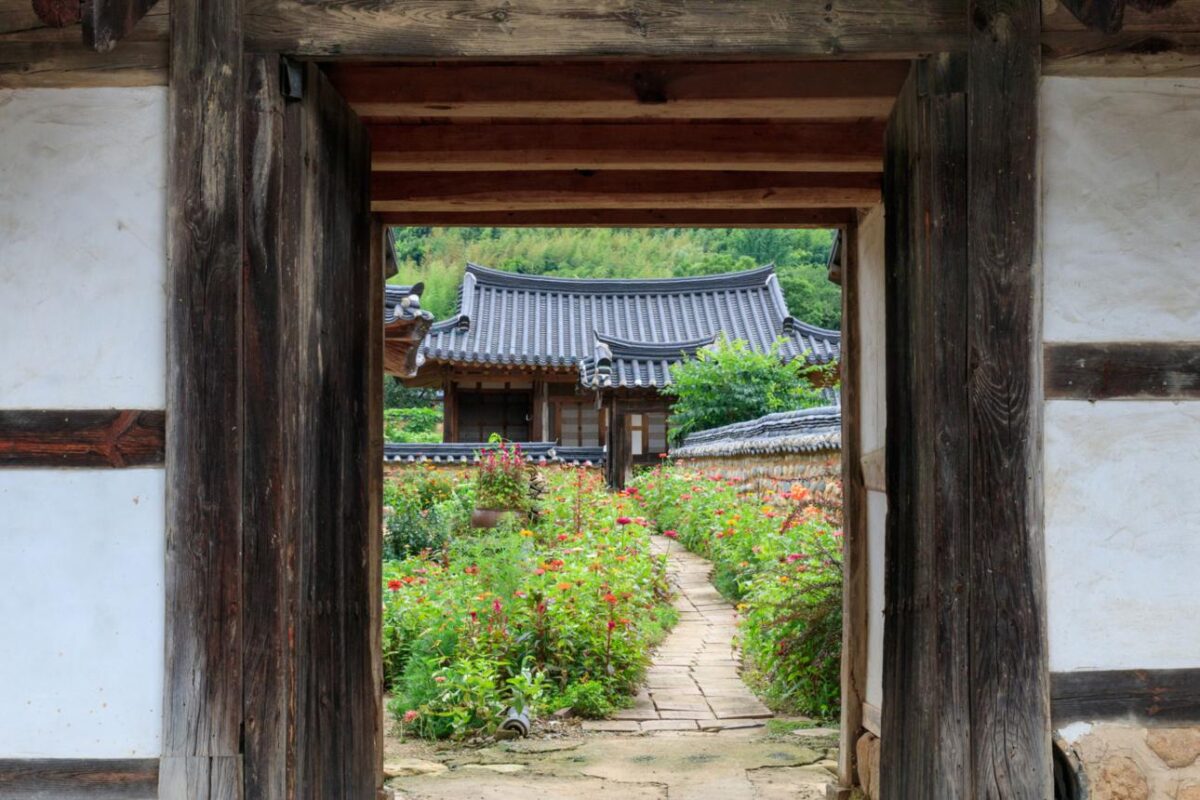 Type in motion: wooden gateway frame opening to flowering garden symbolizing constant design structure meeting changing seasonal conditions and growth