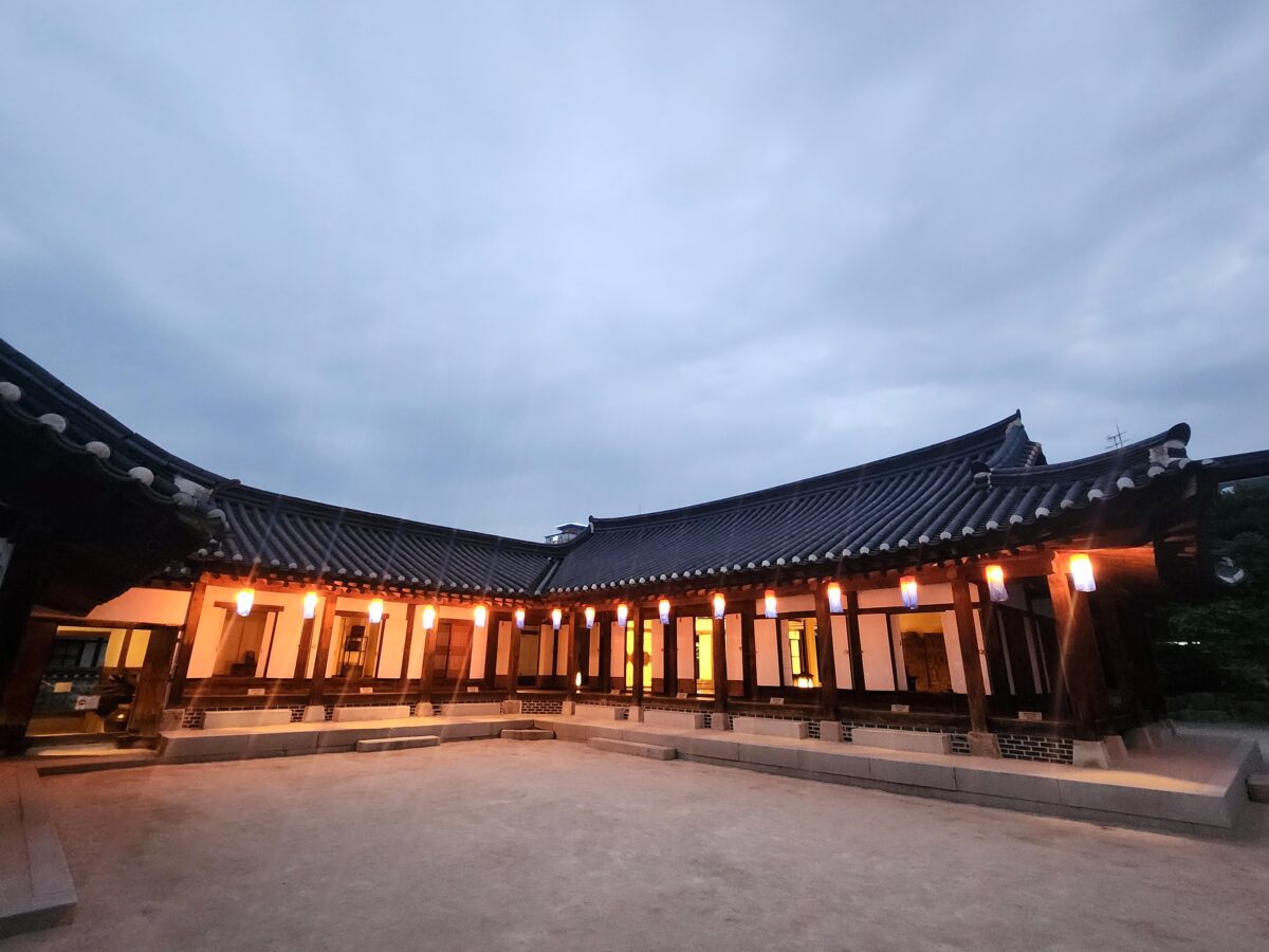 quarter-life crisis ending — Korean hanok courtyard at dusk with lanterns showing quiet structural clarity