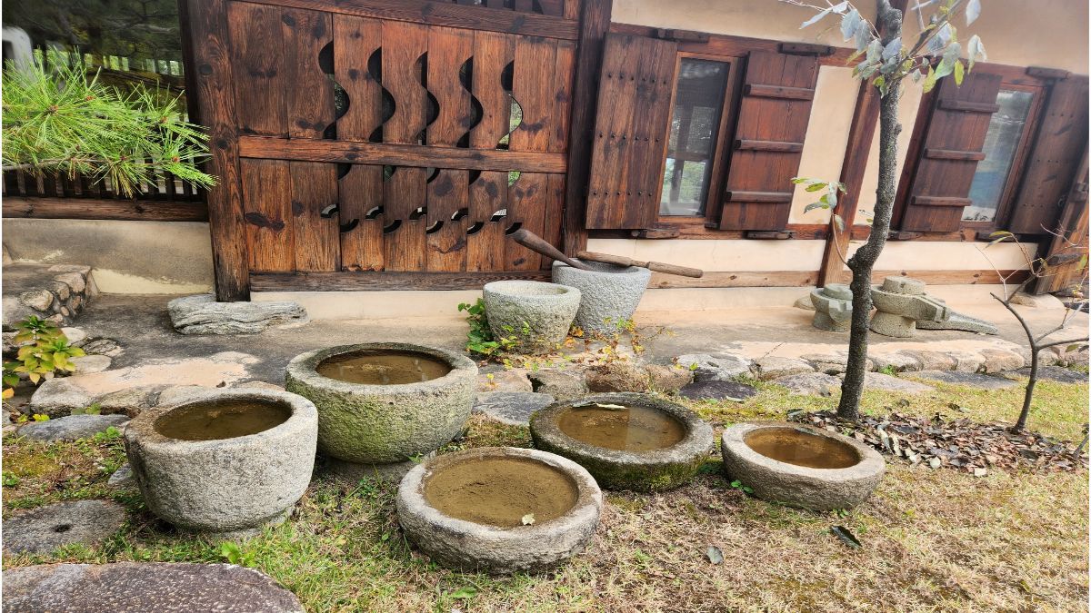 scared of being loved — stone water basins in Korean courtyard beside wooden hanok wall
