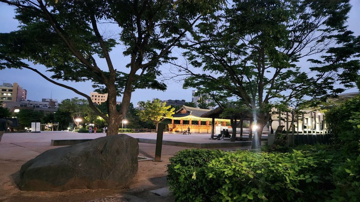 dragon hour meaning in astrology — a quiet Korean park at twilight with a lit pavilion glowing between trees