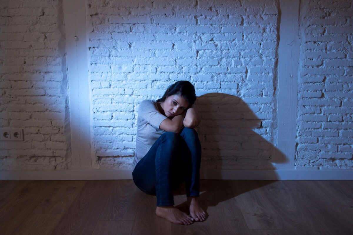 Woman stuck in the wrong major, crouched against wall, feeling trapped and confined