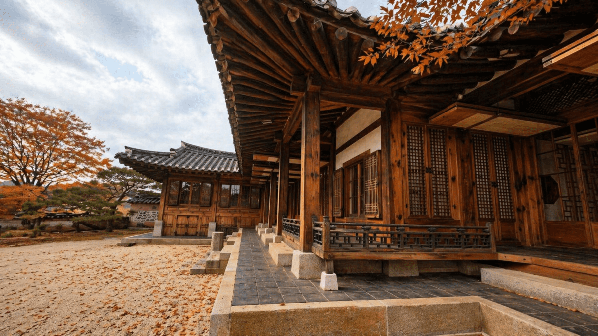 winter threshold astrology meaning — a hanok exterior with deep red maple leaves scattered across the courtyard