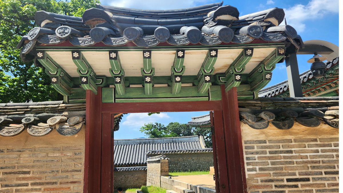 Yin fire stem in K-Saju — traditional Korean gate framed by ornate green brackets and a brick wall.