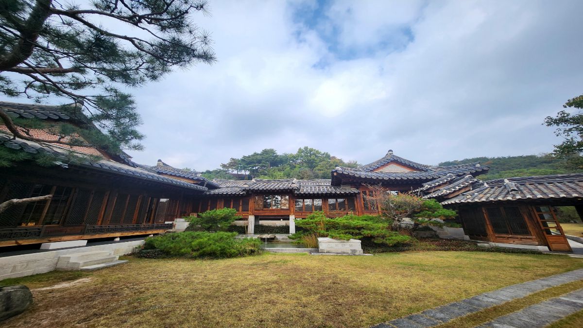 A traditional Korean hanok courtyard with quiet pine trees and a small reflecting pond, symbolizing the yin metal stem in K-Saju
