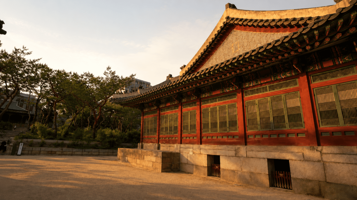 Late afternoon sunlight on a Korean palace hall with patterned eaves, anchoring the afternoon cycle meaning in astrology.