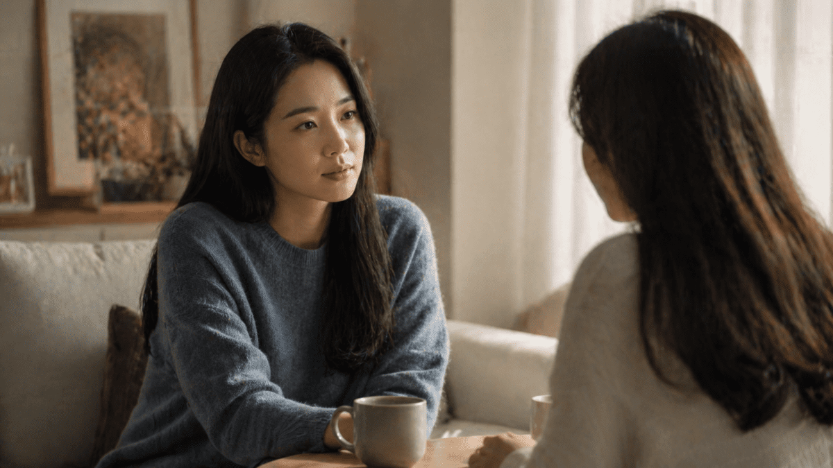 Two women in conversation in a warm living room, one reaching toward the other with gentle attention, representing secure attachment style and emotional safety in relationships.