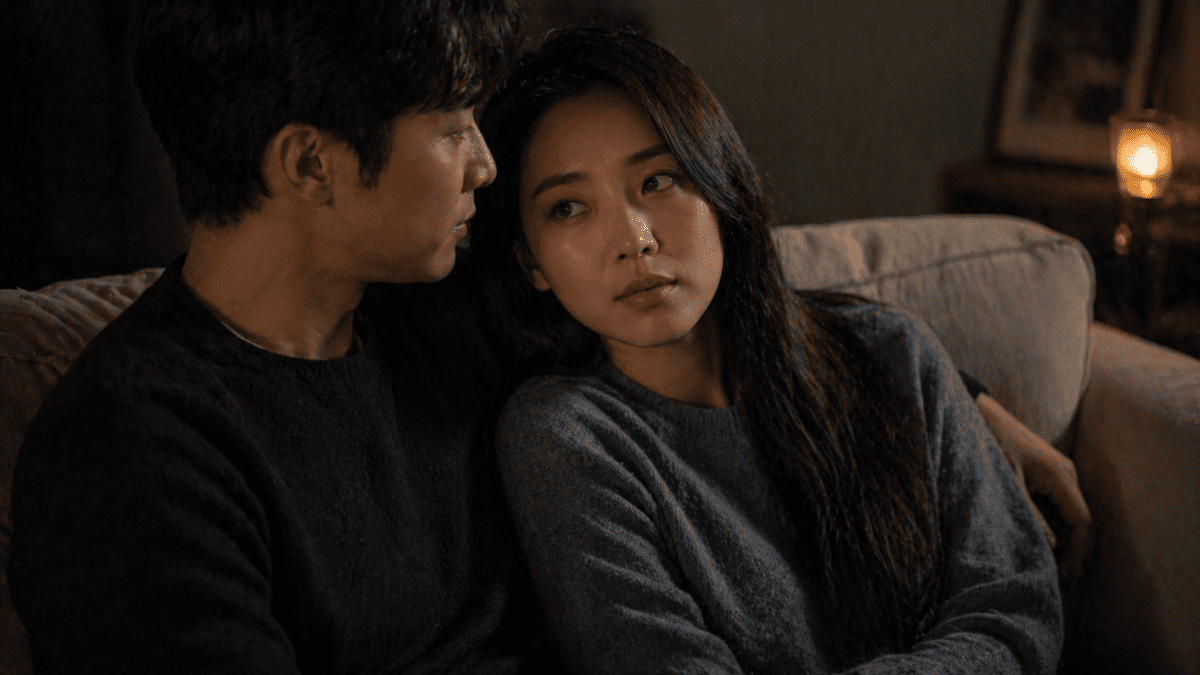 A couple sitting together on a couch in intimate conversation, demonstrating secure attachment style through relaxed body language, mutual attention, and emotional closeness in a warm home environment.