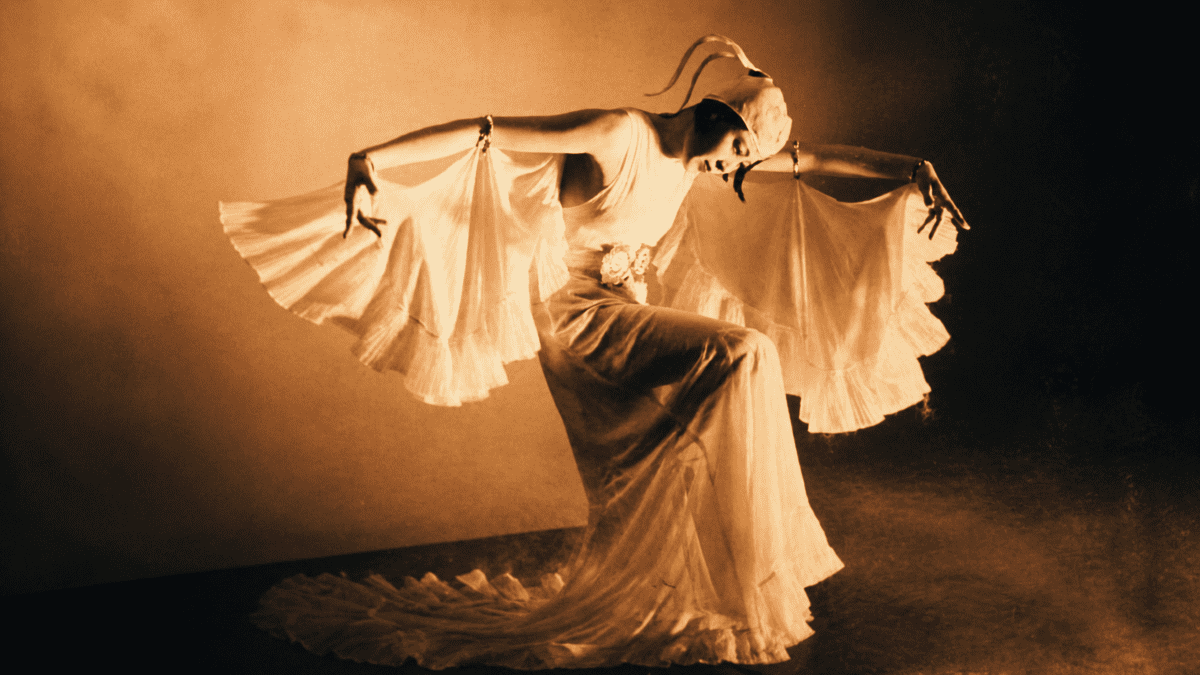 Choi Seung-hee performing an expressive modern dance pose in flowing white costume under dramatic stage lighting.