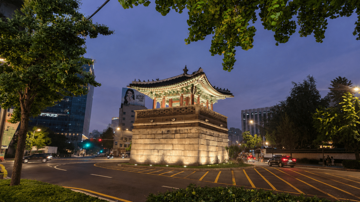 group dynamics concept image of Seoul’s Dongsipjagak pavilion at night, blending Korean tradition with modern urban flow
