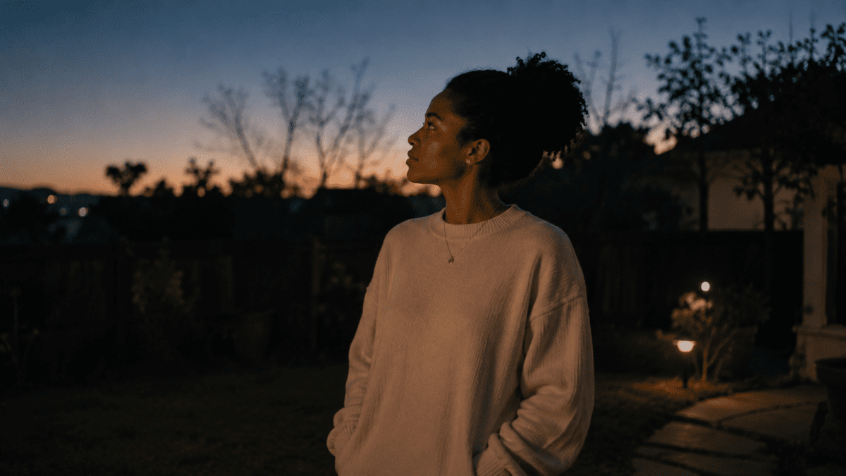 Woman standing outside at dusk gazing into the distance, capturing the midnight hour meaning in astrology before dawn.