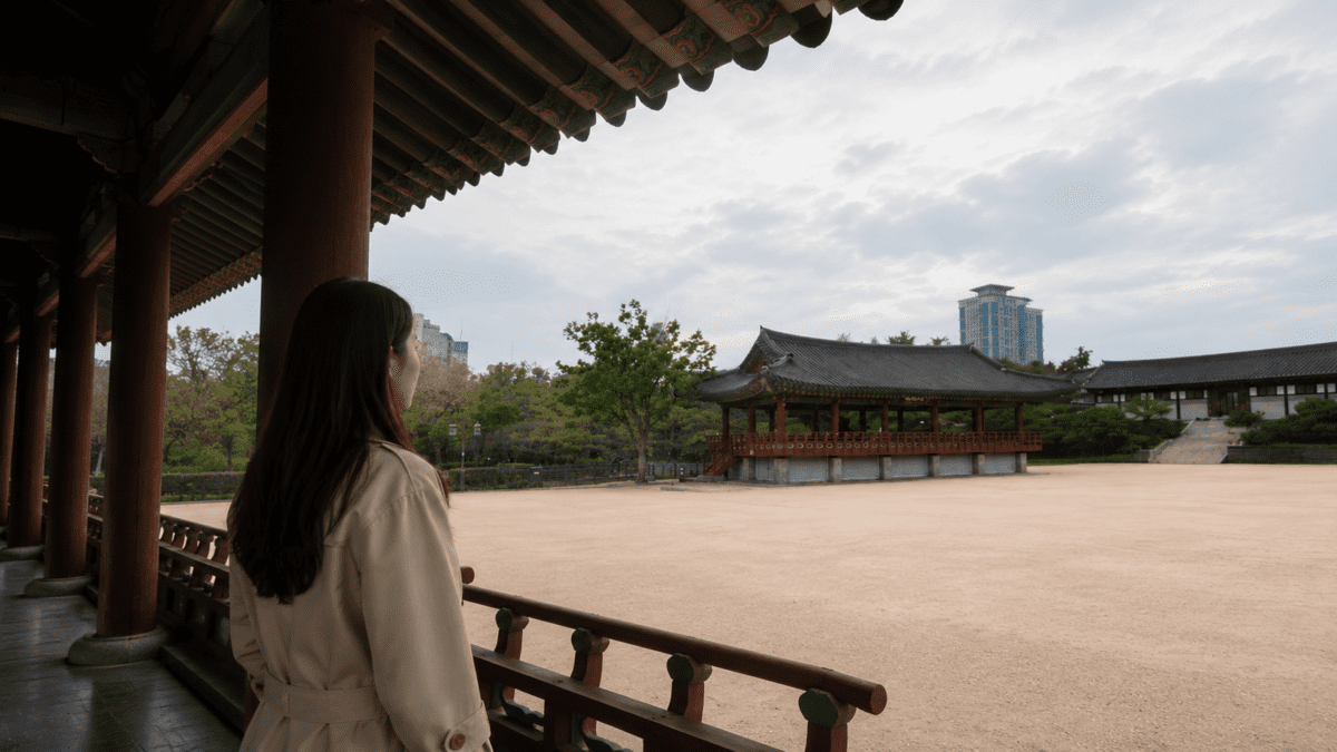 Woman stands alone beneath a traditional pavilion, holding back her feelings out of fear of becoming a burden.