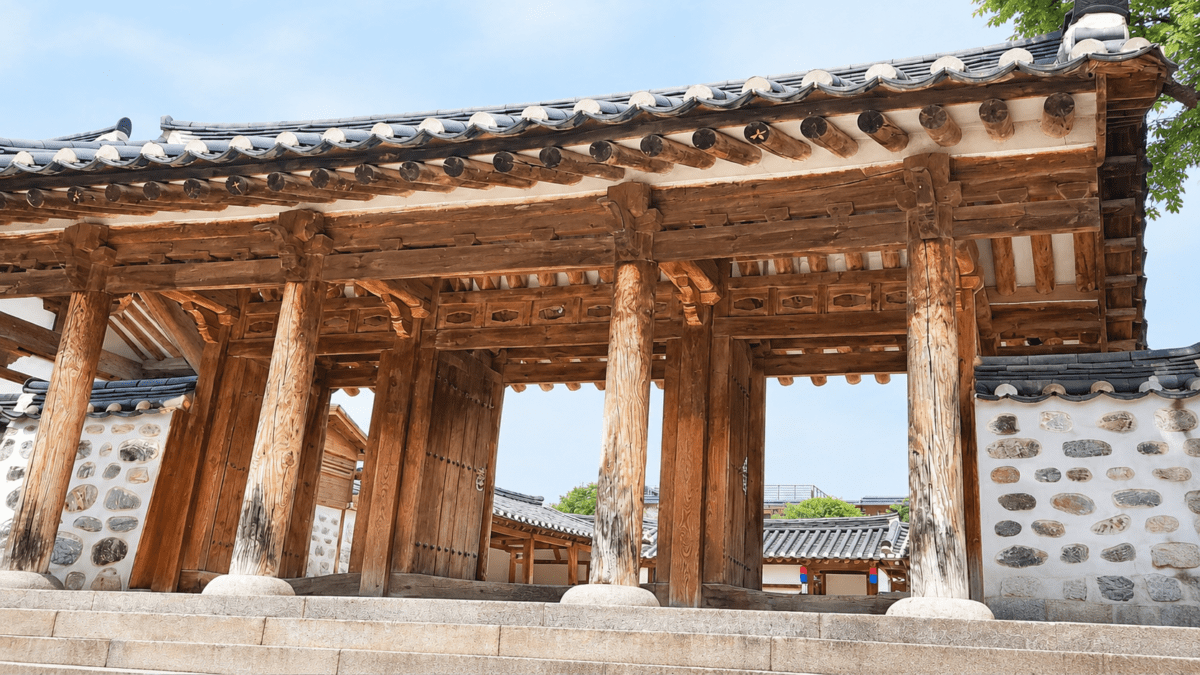 Wooden hanok gate with tiled eaves under bright summer sky, anchoring the summer solstice meaning in astrology.