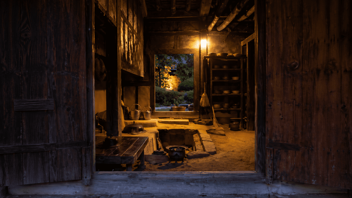 A traditional Korean temple kitchen illuminated by firelight before dawn, representing temple slow food—illustrating how the kitchen opens at 3 AM, where time is not an obstacle but the ingredient itself, and every element already knows what it needs.
