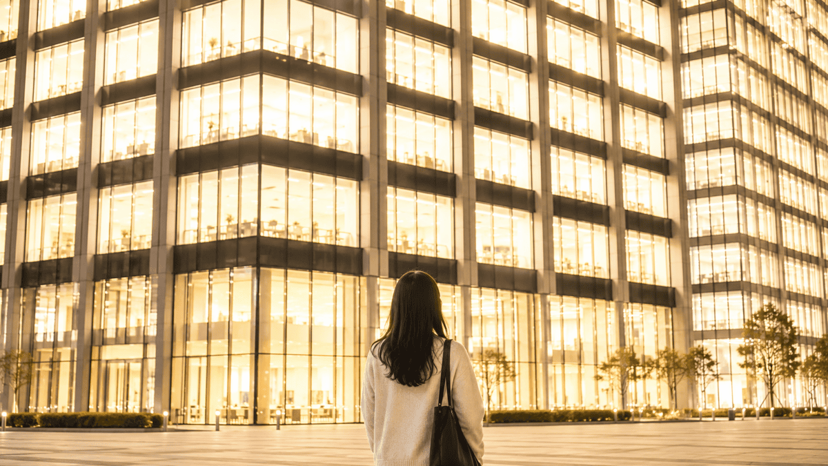 A woman standing before a building of illuminated windows at night — Nam June Paik television as art and the gaze that changed how we see screens