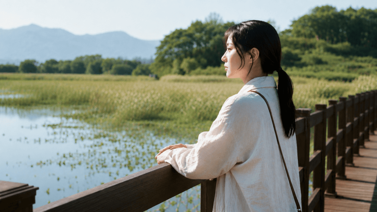 Woman leans on a wetland boardwalk railing, gaze quiet — the morning after a sleepless night brings presence, not preparation.