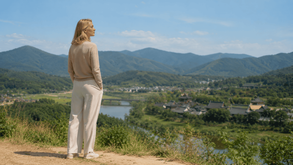 Woman stands back on a hillside taking in a wide Korean landscape — the career break that restores perspective.